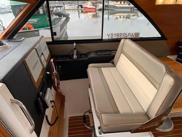 Slide: The Image of Interior of a 2021 Cutwater C-32 Coupe with beige seating and wood trim, overlooking a marina. - 13