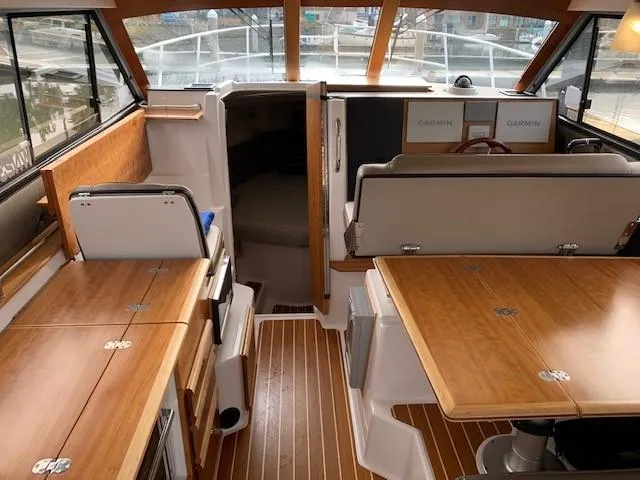 Slide: The Image of Interior of a 2021 Cutwater C-32 Coupe with wood flooring and table, Garmin equipment visible. - 12