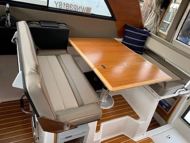 Slide: The Image of Interior of a 2021 Cutwater C-32 Coupe featuring a sleek wooden table and cushioned seating. - 16