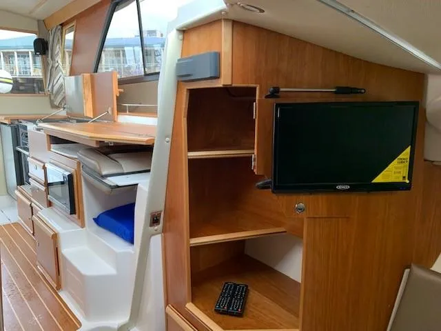 Slide: The Image of Interior of a 2021 Cutwater C-32 Coupe featuring wood cabinetry and a small TV. - 20