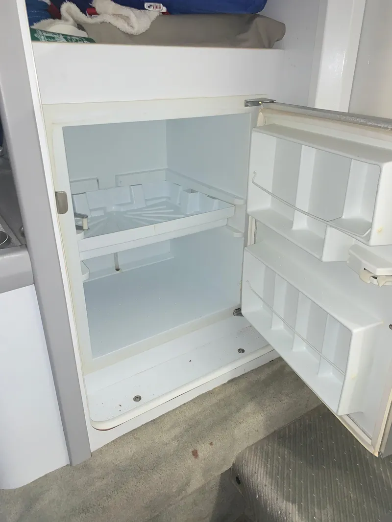 Slide: The Image of An open refrigerator inside a boat, featuring empty shelves and door compartments. - 25