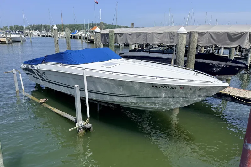 The Image of White 1995 Formula 303 SR-1 boat docked with blue cover in marina. - 1