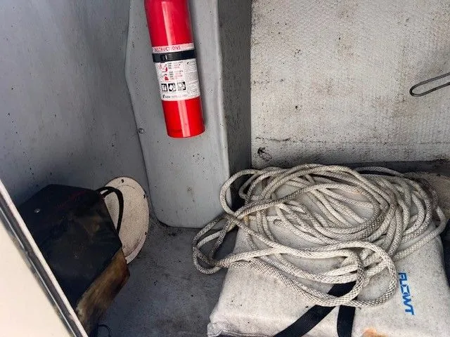 Slide: The Image of A fire extinguisher is mounted on a boat wall, with a rope coiled on a cushion nearby. - 21
