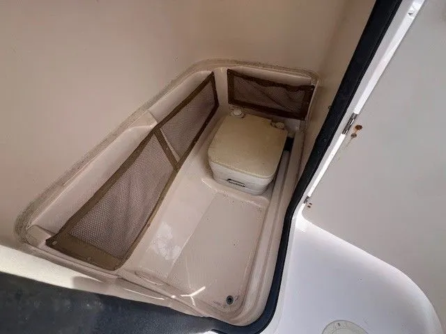 Slide: The Image of The image shows a small boat toilet with a portable toilet and mesh pockets on the walls. - 24
