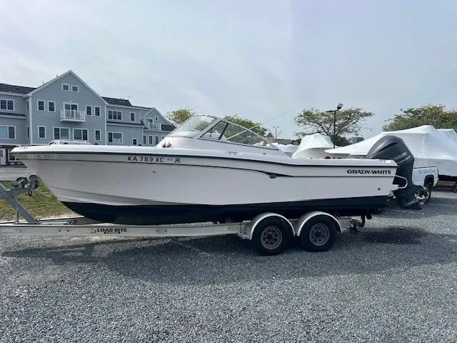 Slide: The Image of A 2003 Grady-White 225 Express boat on a trailer in a gravel lot. - 16