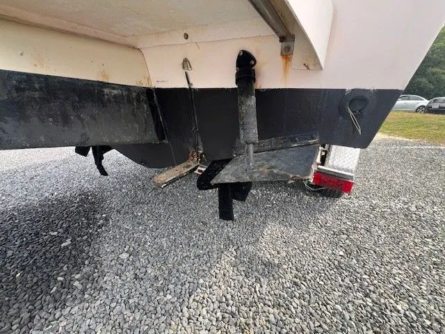 Slide: The Image of The image shows the hull of a 2003 Grady-White 225 Express boat on a gravel surface. - 14