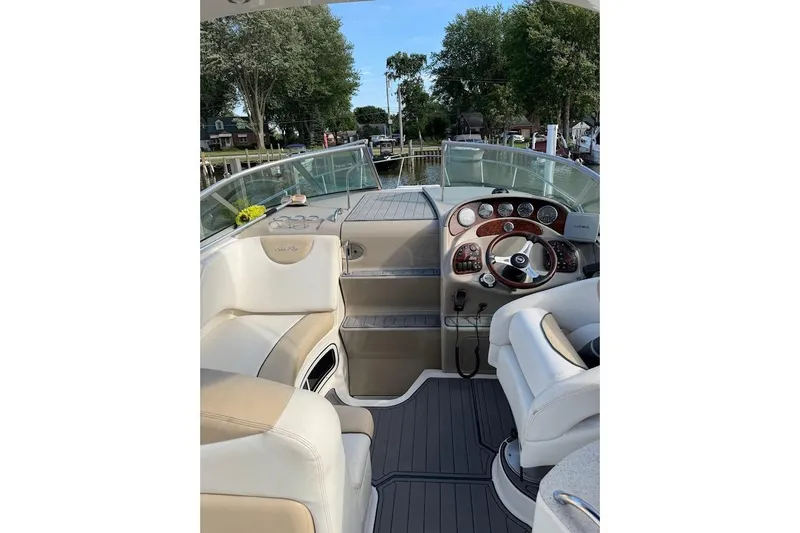 Slide: The Image of 2008 Sea Ray Sundancer 280 cockpit with steering wheel, dashboard, and seating, docked near trees. - 15