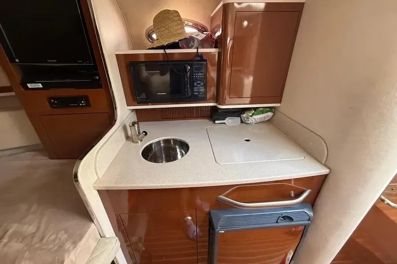Slide: The Image of 2008 Sea Ray Sundancer 280 galley with sink, microwave, and storage cabinets. - 20