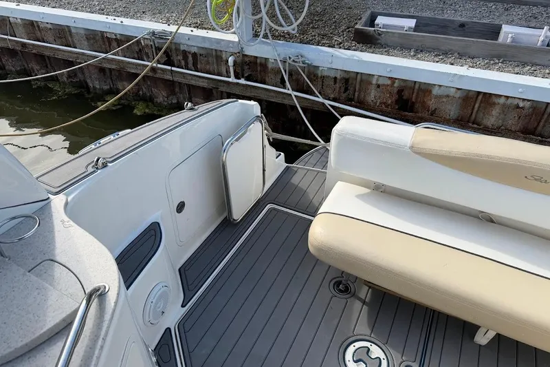 Slide: The Image of 2008 Sea Ray Sundancer 280 boat interior with beige seating and gray flooring at dock. - 10