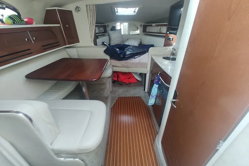 Slide: The Image of Interior of 2009 Sea Ray Sundancer 280, featuring cozy seating, table, and compact kitchenette. - 27