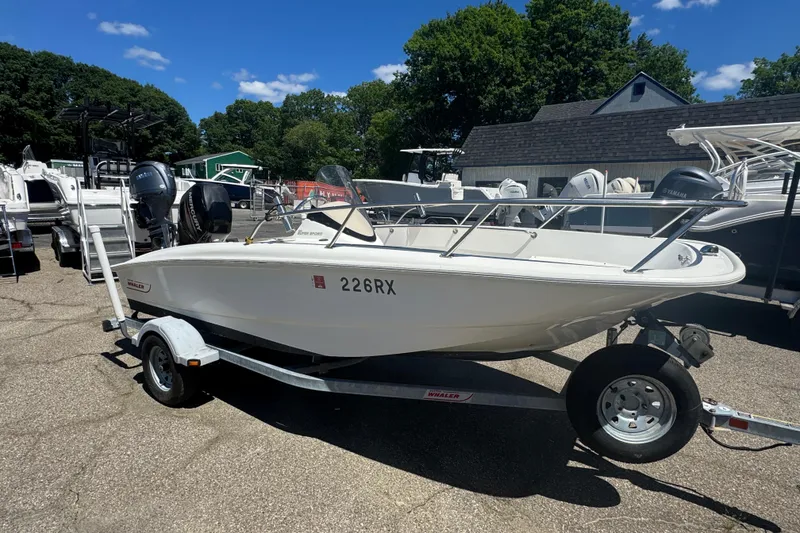 Slide: The Image of 2014 Boston Whaler 150 Super Sport boat on trailer, parked outdoors under clear sky. - 5