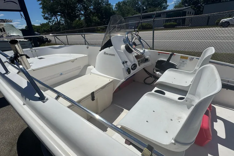 Slide: The Image of 2014 Boston Whaler 150 Super Sport boat interior with seating and steering console. - 2