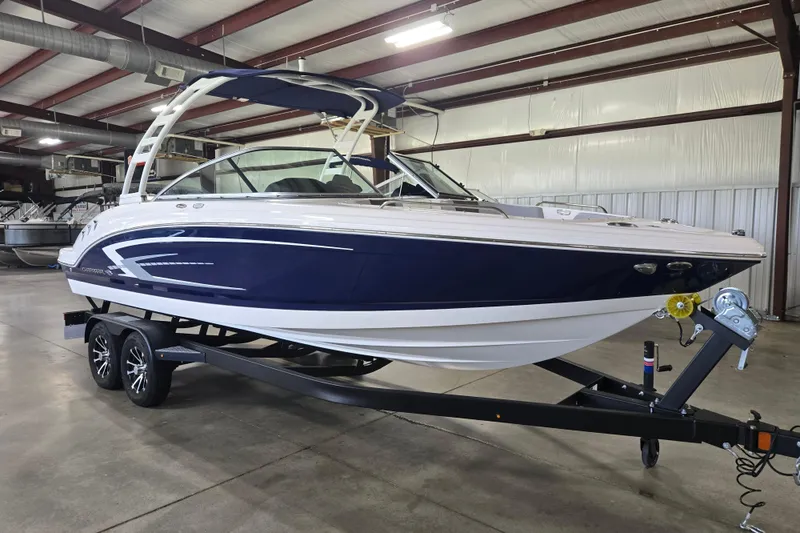 The Image of 2023 Chaparral 23 SSi boat in showroom, featuring sleek blue and white design on trailer. - 1