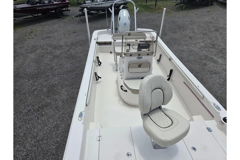 Slide: The Image of 2022 Carolina Skiff 21 LS boat interior with seating and console, parked on gravel. - 15