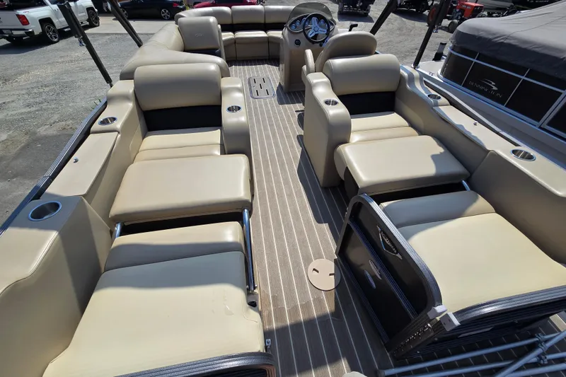 Slide: The Image of 2016 Manitou 23 Oasis SR pontoon boat interior with beige seating and steering console. - 11