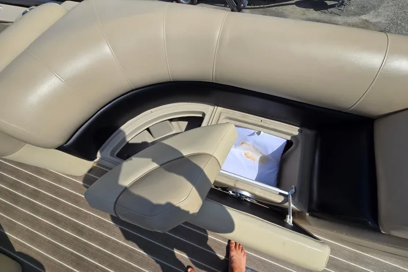 Slide: The Image of 2016 Manitou 23 Oasis SR boat interior with beige seating and storage compartment. - 20