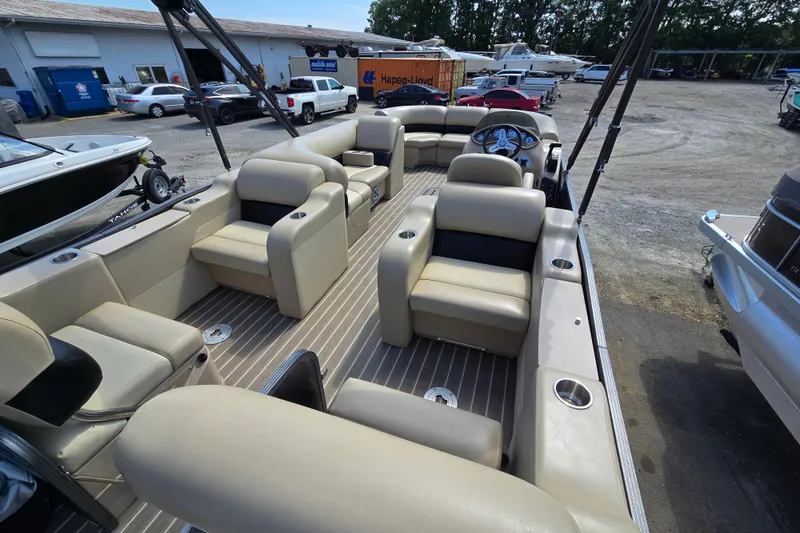 Slide: The Image of 2016 Manitou 23 Oasis SR pontoon boat interior with beige seating and steering console. - 10