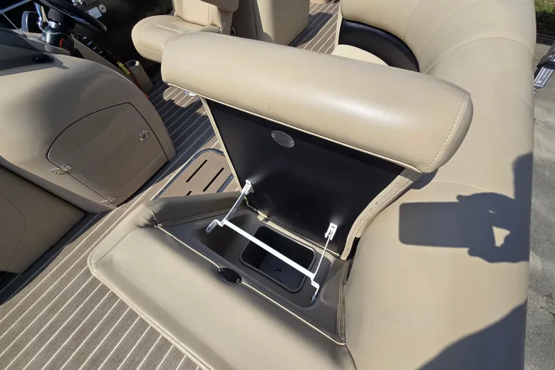 Slide: The Image of 2016 Manitou 23 Oasis SR boat interior with beige seating and storage compartment. - 19