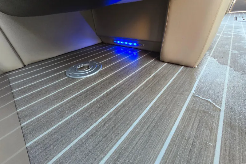 Slide: The Image of 2016 Manitou 23 Oasis SR boat interior with striped flooring and blue LED lighting. - 38