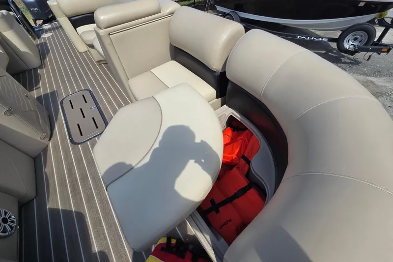 Slide: The Image of 2016 Manitou 23 Oasis SR boat interior with beige seating and life jackets stored. - 18