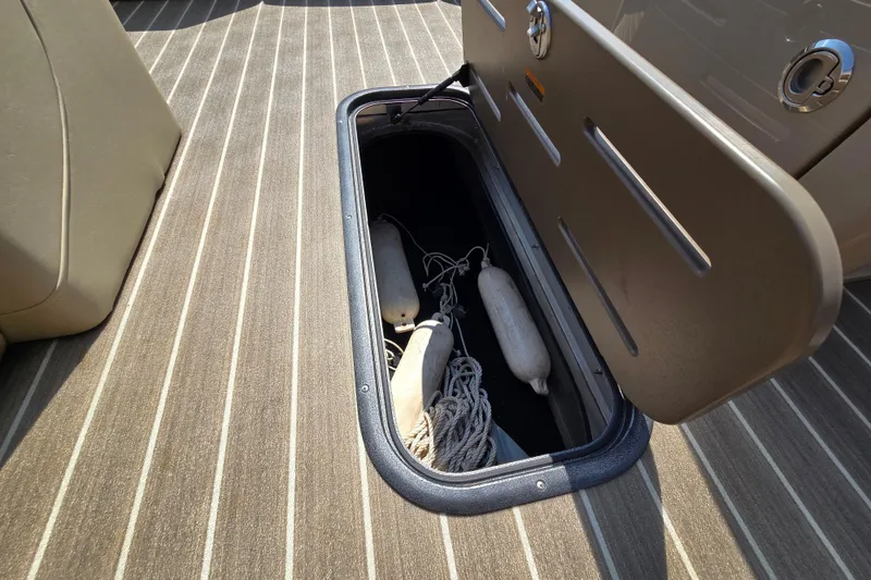 Slide: The Image of Open storage compartment on 2016 Manitou 23 Oasis SR boat with fenders and ropes inside. - 35