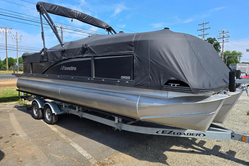Slide: The Image of 2016 Manitou 23 Oasis SR pontoon boat on trailer, covered with black tarp. - 1