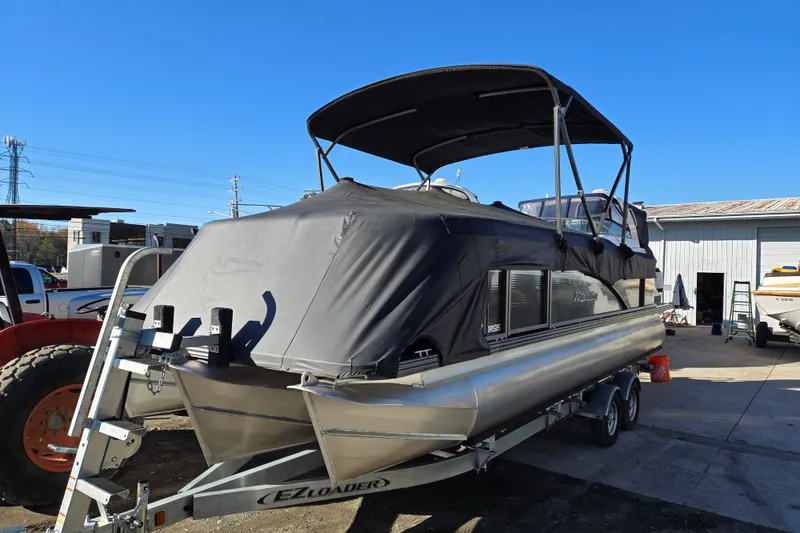 Slide: The Image of 2016 Manitou 23 Oasis SR pontoon boat on trailer, covered and parked outdoors. - 2