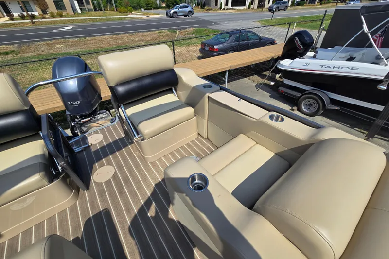 Slide: The Image of 2016 Manitou 23 Oasis SR pontoon boat interior with beige seating and Yamaha 150 engine. - 14
