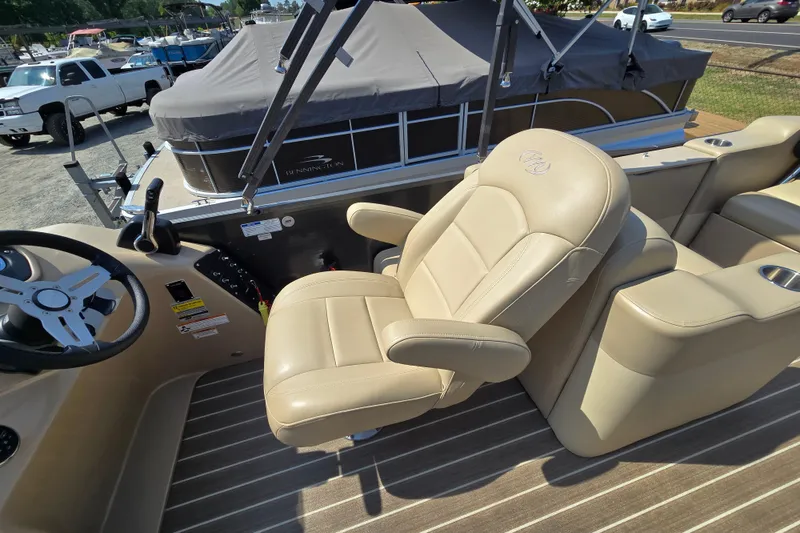 Slide: The Image of 2016 Manitou 23 Oasis SR boat interior with beige captain's chair and steering wheel. - 34