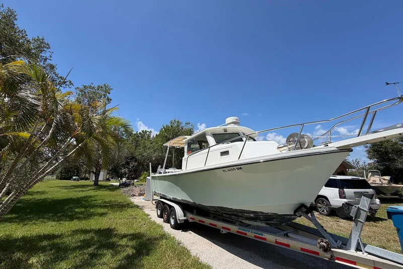 Slide: The Image of 2016 Parker 2820 XLD Sport Cabin boat on trailer, parked outdoors under clear blue sky. - 3