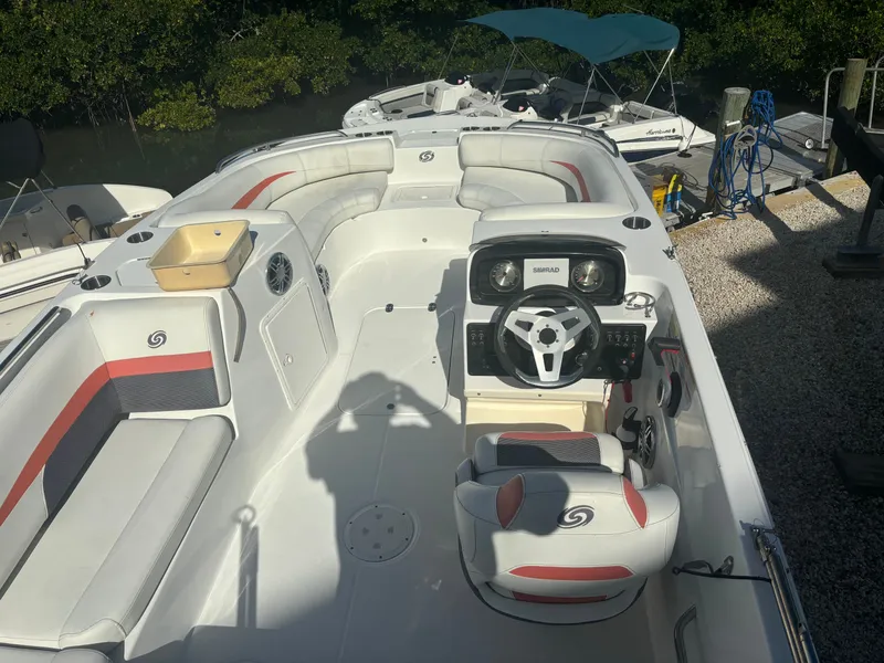 Slide: The Image of The image shows a 2021 Hurricane 188 SunDeck Sport -OB boat. It features white and red upholstery, a central helm, and is docked in a marina area. - 5
