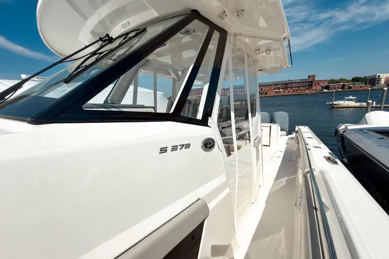 Slide: The Image of 2023 Pursuit S 378 Sport boat docked by waterfront, showcasing sleek design and modern features. - 5