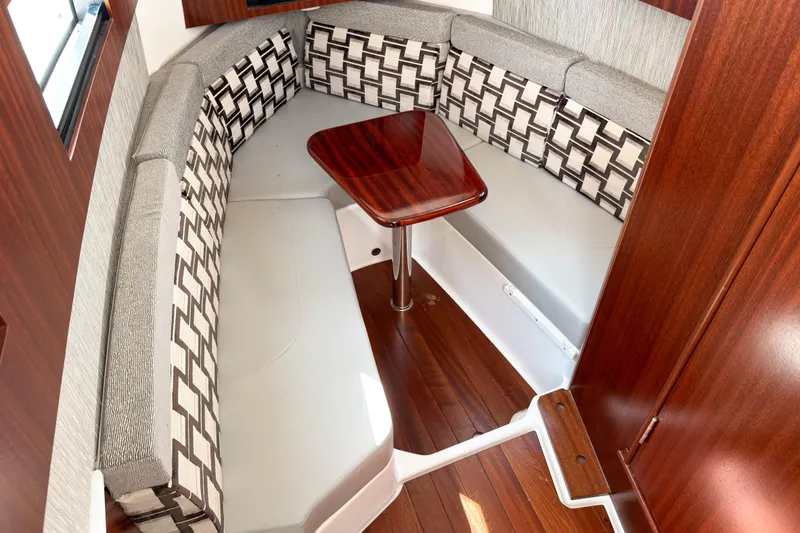 Slide: The Image of 2023 Pursuit S 378 Sport interior with cushioned seating and wooden table. - 11