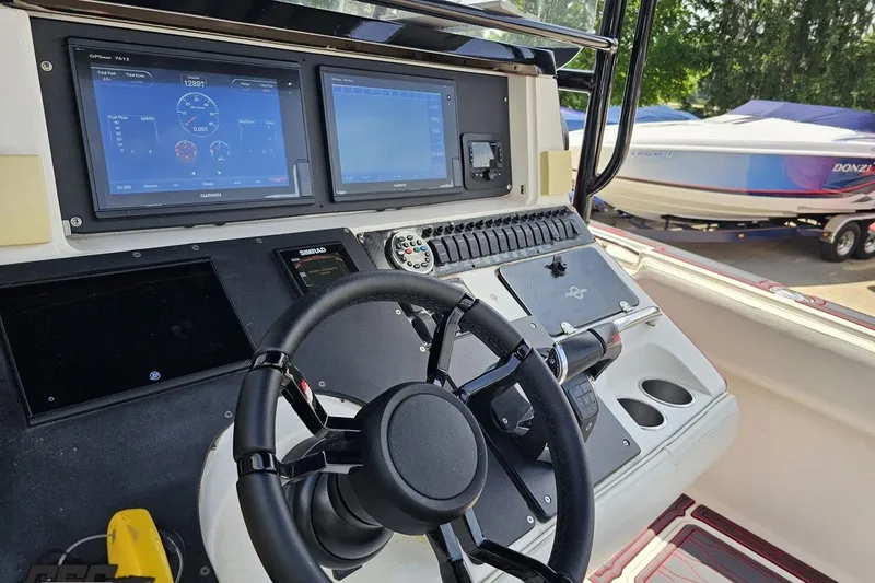 Slide: The Image of 2005 Fountain 34 Sportfish CC Open Bow dashboard with Garmin displays and steering wheel. - 69