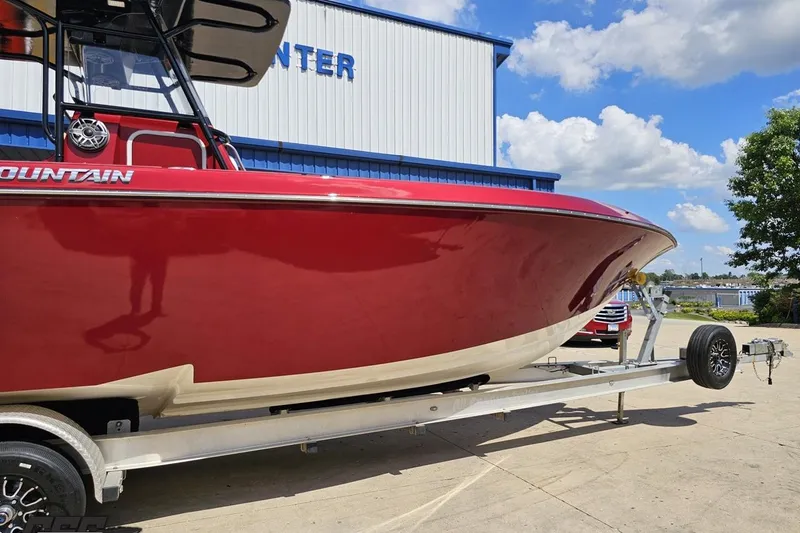 Slide: The Image of 2005 Fountain 34 Sportfish CC Open Bow boat on trailer, red hull, sunny day. - 10