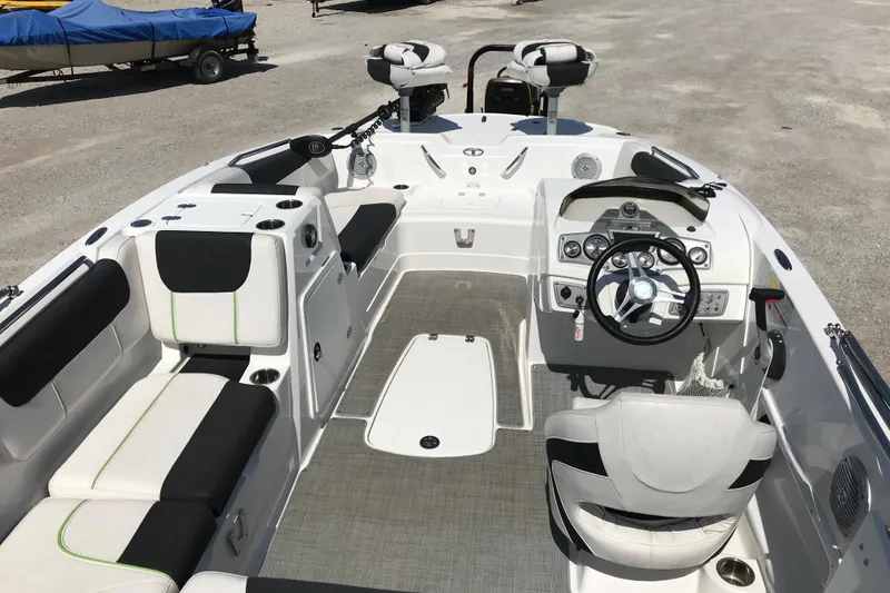 Slide: The Image of 2021 Tahoe 1950 boat interior with modern seating and steering wheel, parked on gravel. - 9