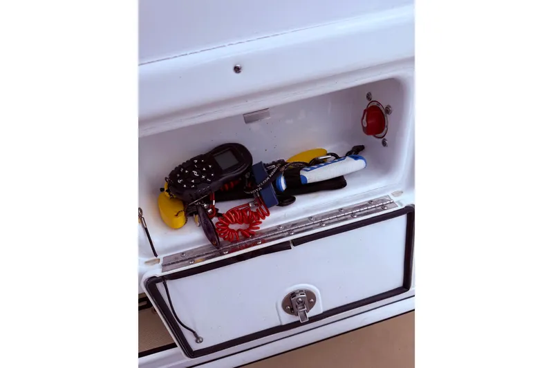 Slide: The Image of A storage compartment on a 2017 Sportsman Open 212 Center Console boat with various items. - 27