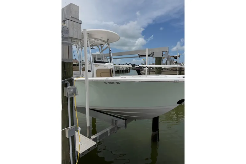 Slide: The Image of 2017 Sportsman Open 212 Center Console boat docked on a lift under a cloudy sky. - 2