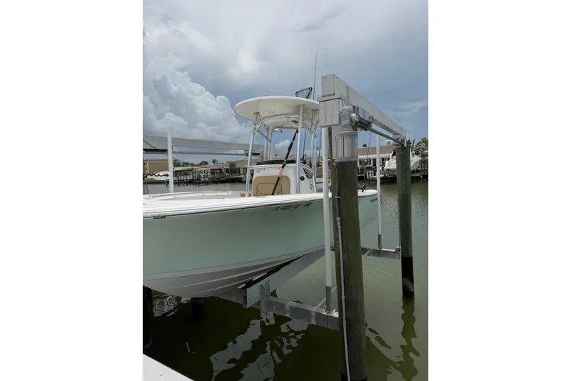 Slide: The Image of 2017 Sportsman Open 212 Center Console boat on lift, docked by waterfront homes. - 3