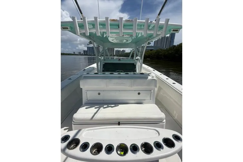 Slide: The Image of 2016 SeaHunter 41 Tournament boat interior with rod holders and seating, docked near cityscape. - 16