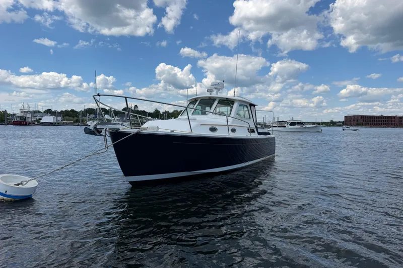 Slide: The Image of 2004 Back Cove 29 boat moored on a sunny day with a cloudy sky backdrop. - 2