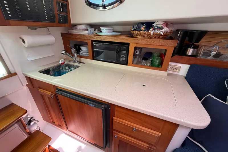 Slide: The Image of 2004 Back Cove 29 boat interior kitchen with sink, microwave, and wooden cabinetry. - 17