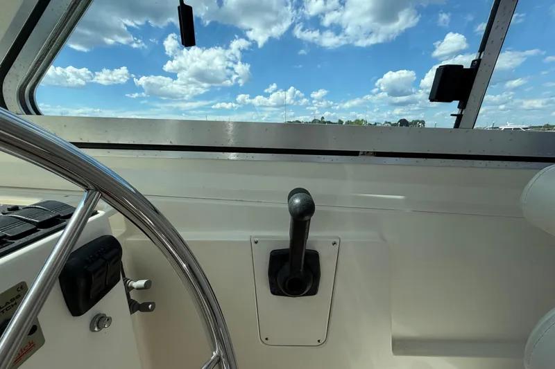 Slide: The Image of Interior view of a 2004 Back Cove 29 boat, featuring steering wheel and throttle control. - 13