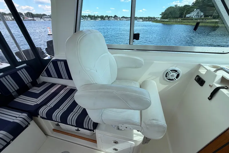 Slide: The Image of Interior of a 2004 Back Cove 29 boat with white seating and striped cushions. - 8