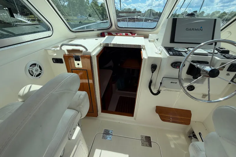 Slide: The Image of 2004 Back Cove 29 boat interior with Garmin navigation, steering wheel, and cabin entrance. - 14