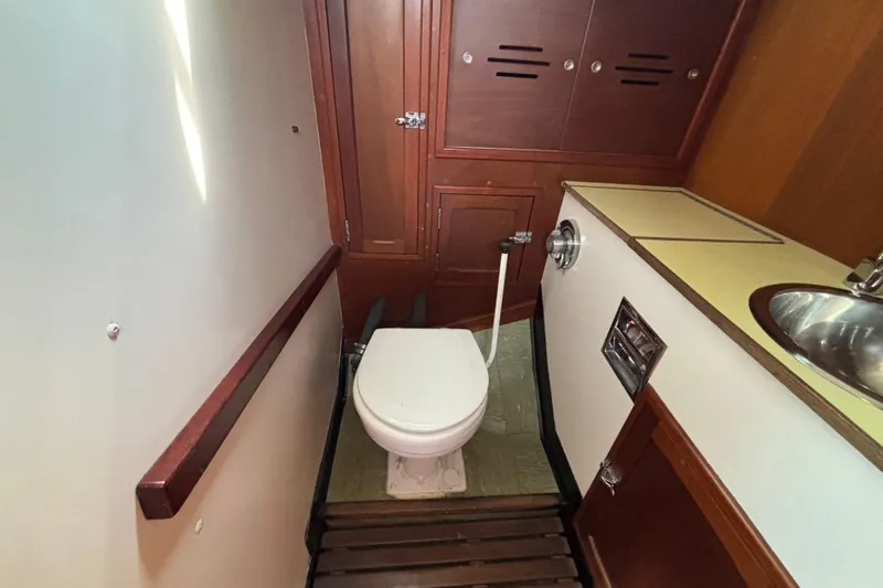 Slide: The Image of 1974 Hinckley Bermuda 40 MKIII yacht bathroom with toilet, sink, and wooden cabinetry. - 40
