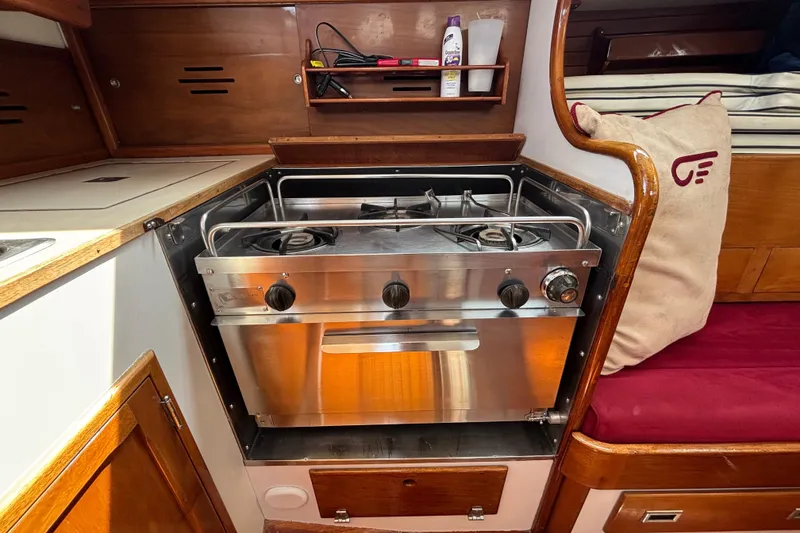 Slide: The Image of 1974 Hinckley Bermuda 40 MKIII yacht galley with stainless steel stove and wooden cabinetry. - 30