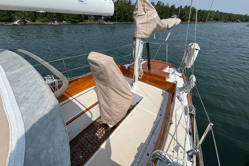 Slide: The Image of 1974 Hinckley Bermuda 40 MKIII sailboat deck with covered equipment, moored on calm water. - 13
