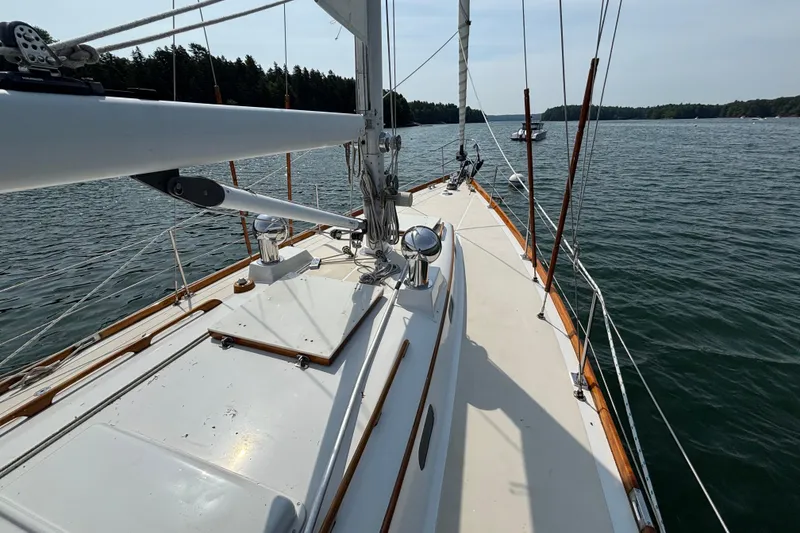 Slide: The Image of 1974 Hinckley Bermuda 40 MKIII sailboat deck on calm waters, showcasing classic design. - 7