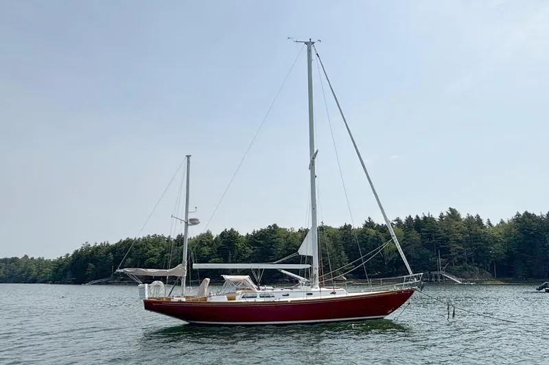 Slide: The Image of 1974 Hinckley Bermuda 40 MKIII sailboat anchored in a serene lake setting. - 5